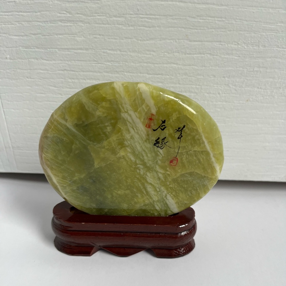 Serpentine Freeform Stone Displayed On A Wooden Stand.